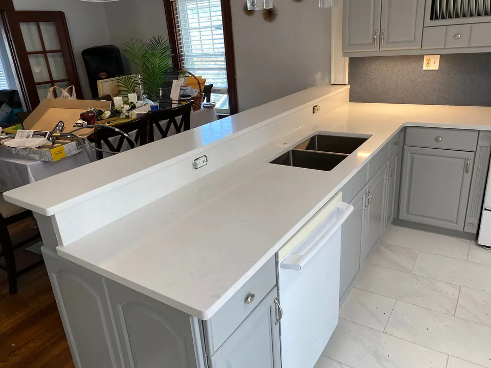 White quartz counter with a raised bar ledge and a double-bowl undermount sink