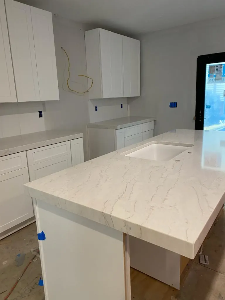 White island with soft beige veins and a white undermount sink in a kitchen still under construction