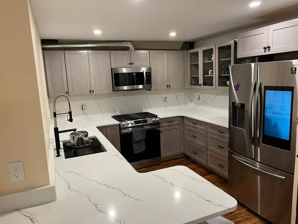 L-shaped kitchen with white veined counters and the same stone running up the wall as a full-height backsplash