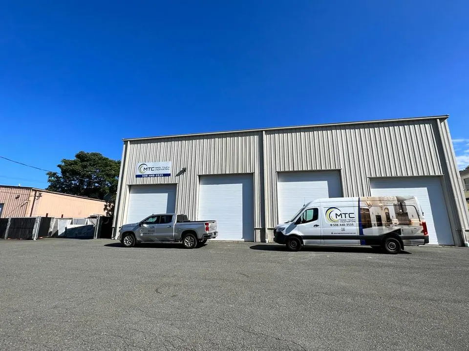 The Magic Touch Countertops building, a gray metal shop with three garage doors, the van and a pickup in front