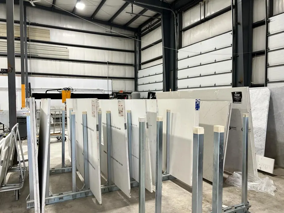 Inside the shop: white slabs standing on steel racks under the high ceiling