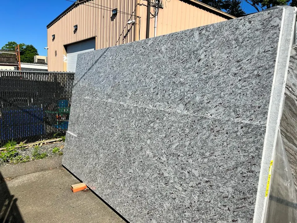 Gray and white granite slab with a coarse speckled pattern, standing in the yard