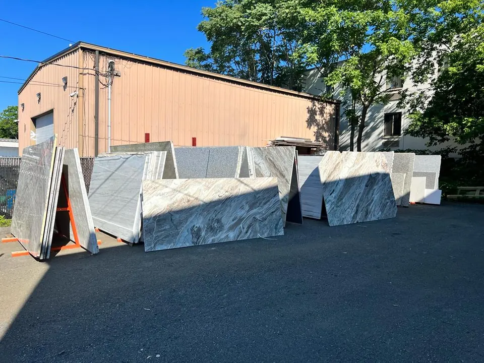 The slab yard behind the shop, rows of stone slabs on A-frames
